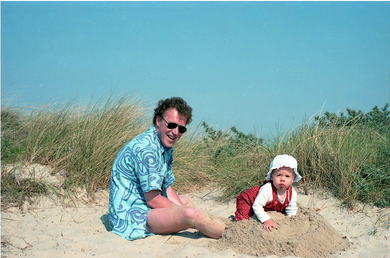 A man and a young child playing in the sand dunes near the seaside village of Vrouwenpolder, Netherlands, photographed during a family holiday in June 1985.