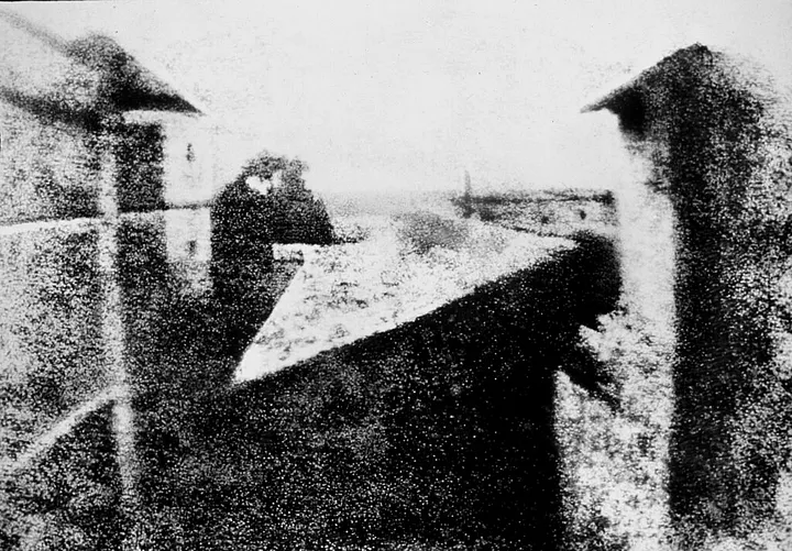 View from a window overlooking farm buildings and rooftops at Le Gras, France, photographed by Nicéphore Niépce in 1826.