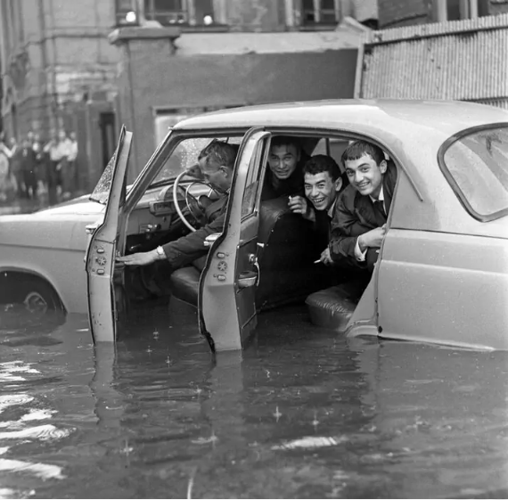 Young men sit inside a partially submerged car on a flooded Moscow street after heavy rainfall.